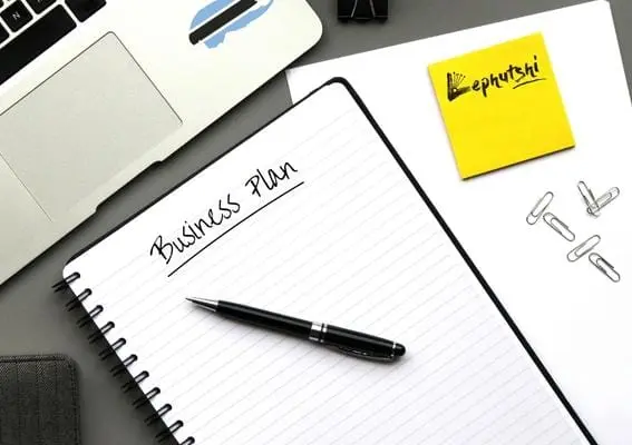 Business Plan Basics: Botswana Template & Guide 1 Business Plan written on a notepad with a pen, MacBook with Botswana flag, and Lephutshi logo on a sticky note
