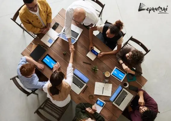 Business Plan Basics: Botswana Template & Guide 3 Team working together at a table with devices and paperwork, Lephutshi logo visible, symbolizing collaborative business planning