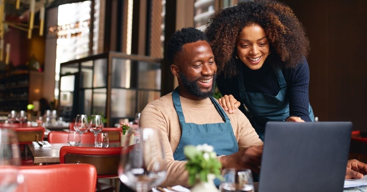 Botswana small-business owner using a laptop and phone as customers contact them